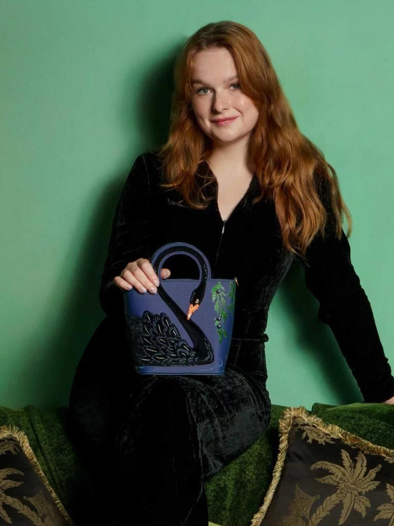 Black Swan Cut Out Handle Tote Model with bag sitting on lap.